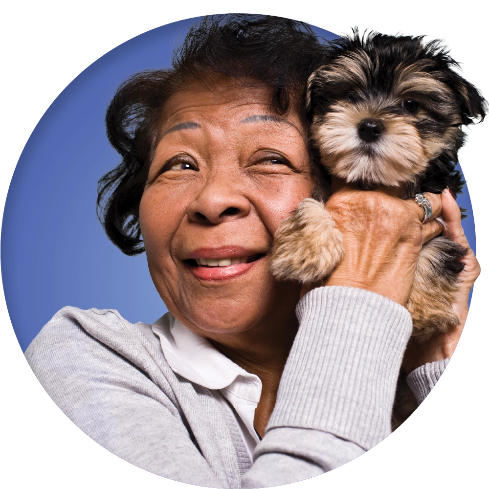 head and shoulder image of smiling Medicare-age woman holding dog
